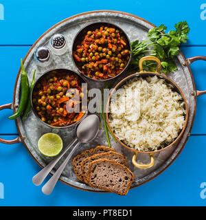 Vegan curry mit grünen Erbsen und Basmatireis auf einem blauen Tisch Tablett serviert, gesunde indische Speisen Stockfoto