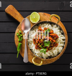 Vegan curry mit grünen Erbsen und Basmatireis auf einem hölzernen Tisch Tablett serviert, gesunde indische Speisen Stockfoto