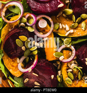 Warmer Salat mit gebackenen Kürbis und rote Rüben mit Rucola und Samen auf einem Marmortisch. Gesunde vegane Küche für die ganze Familie. Stockfoto
