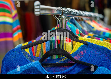 Bunte Kleidung hängen im Regal in einem Markt Stockfoto