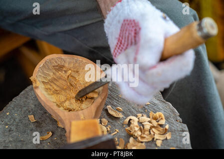Handwerker demonstriert den Prozess der hölzerne Löffel handmade mit Werkzeugen. Die nationalen Handwerk Konzept. Stockfoto