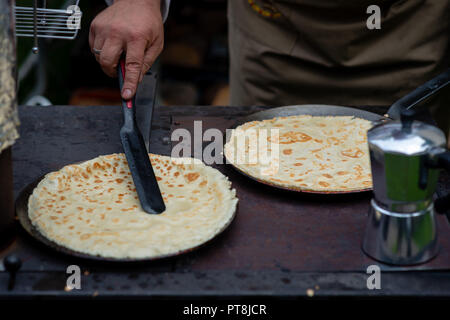 Ein Mann in einem Open-air-Picknick gebackenen Pfannkuchen. Stockfoto