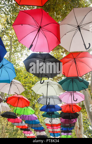 Eine strasse Installation von bunte Sonnenschirme, die in der Luft schweben. Stockfoto