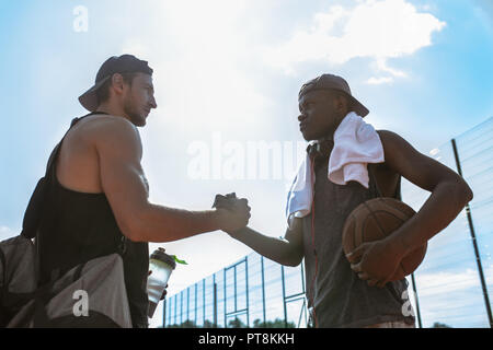 Seitenansicht Porträt von zwei basketballspieler zitternde Hände gegen den blauen Himmel nach dem Match im Freien Gericht, kopieren Raum Stockfoto