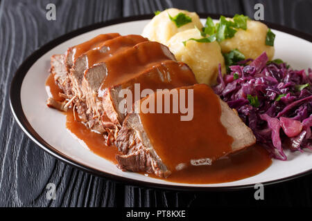 Deutschen Sauerbraten ist ein rinderragout mit einer würzigen Sauce mit Kartoffelklößen und Rotkohl close-up auf einem Teller serviert. Horizontale Stockfoto