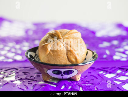 Tag der Toten traditionelle Brot namens Pan de Muerto und Lila papel Picado als Dekoration. Stockfoto