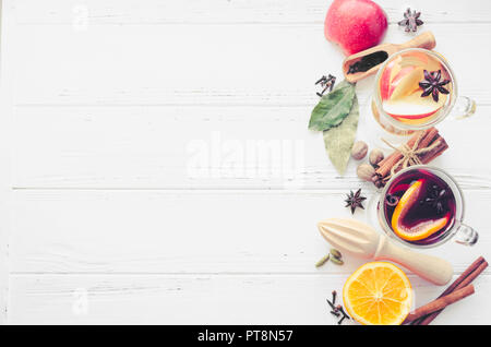 Zwei Gläser verschiedener Art von Glühwein oder Glühwein auf Rot- und Weißwein mit Gewürzen und Zutaten auf weißem Holz- Hintergrund basiert. Hot seaso Stockfoto