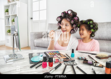 Schöne Mutter tun, Make-up, ihr Kind und ihr mit Freude in den Spiegel zusammen suchen Stockfoto