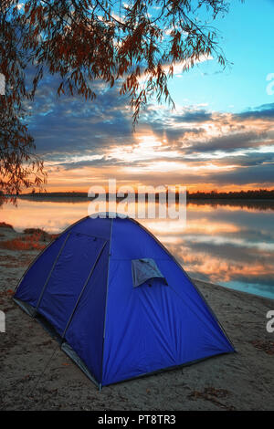 Einem großen blauen Zelt am Ufer des Irtysch Fluss in Sibirien. Im Hintergrund ist eine leuchtende Morgenröte und der aufgehenden Sonne. Stockfoto