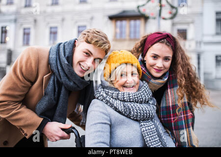 Jugendliche und Senior Großmutter im Rollstuhl auf der Straße im Winter. Stockfoto