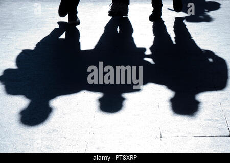 Verschwommene Silhouetten und Schatten der drei man walking city street in der Nacht Stockfoto