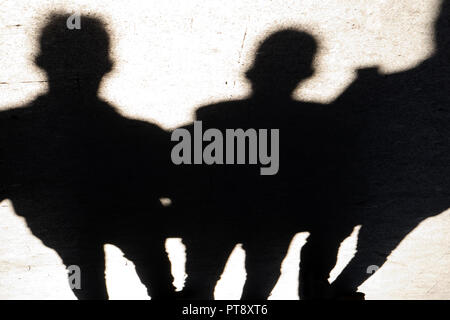 Verschwommene Silhouetten und Schatten der drei Mann auf Stadt Bürgersteig in der Nacht Stockfoto