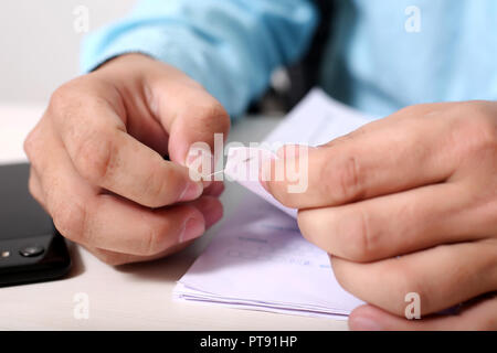 Der Mensch ist Anhängen mehrerer OME-Blatt mit Papier, Stift. Bild des Smartphones auf dem Tisch. Stockfoto