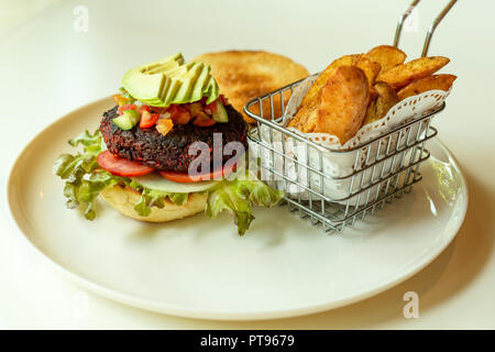 Rote-bete-Burger mit Salat in einem knusprigen Brötchen und Chips Stockfoto