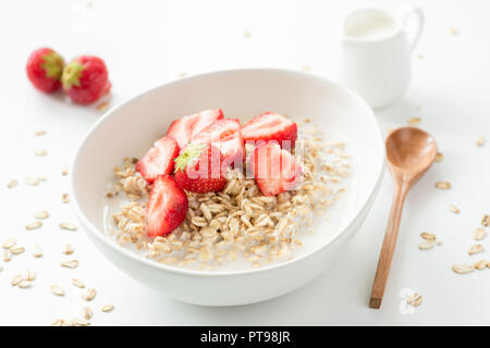 Hafer Porridge mit frischen Erdbeeren und Milch. Gesundes Frühstück Haferbrei mit Früchten auf weißem Hintergrund Stockfoto