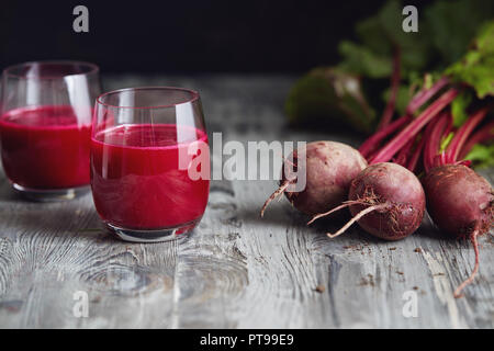 Detox Saft mit frisch gepflückten Bündel von Rote Bete. Frische rote Rüben auf einem Holztisch. Stockfoto