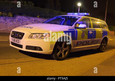 Ein polizeifahrzeug kümmert sich um einen Straße Verkehr Zusammenstoß mit einem umgestürzten Fahrzeug. Stockfoto