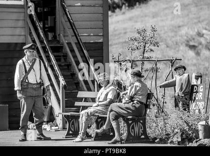 Schwarz & Weiß Schuß von kostümierten Re-enactors die Pause in der Sonne durch das Signal "Schritte & Dig für Sieg Garten im Heritage Railway Station, 1940 die Veranstaltung. Stockfoto