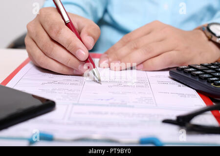 Man füllt Formular mit Pen. Bild von der Zwischenablage, form, Brille, Rechner und Telefon. Stockfoto