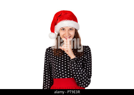 Frau wide eyed bittet um Ruhe- oder bankgeheimnis mit Finger auf die Lippen. emotionale Mädchen in Santa Claus Weihnachten Hut auf weißem Hintergrund. Holiday c Stockfoto