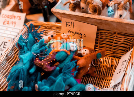 Kleine blaue und orange handgefertigte Puppe Schlüsselanhänger für den Verkauf in einem Weidenkorb zu einem Charity Shop in Matlock Stockfoto