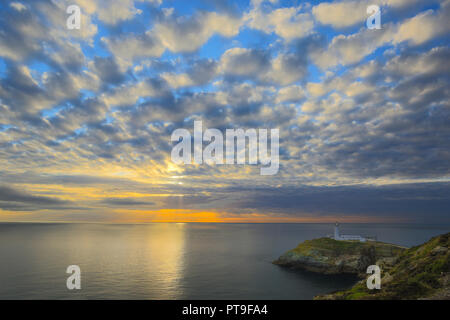 Abend Landschaft der untergehenden Sonne und dramatischer Abendhimmel mit Blick aufs Meer in Richtung South Stack Lighthouse, Anglesey, Nordwales. Altocumului. Stockfoto