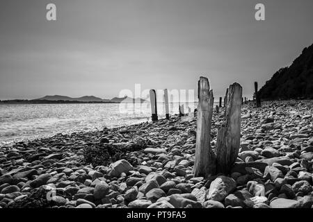 Schwarz-weiß, arty, Landschaft vom Kiesstrand auf Anglesey mit Blick über Menai Strait Wasser in Richtung Yr Eifl Berge (die Rivalen). Stockfoto