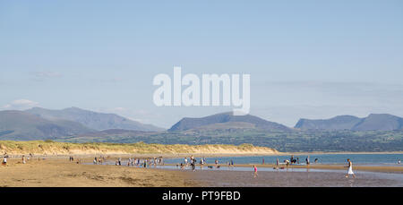 Panorama-Landschaft: Familien am Newborough Warren Beach, Anglesey, Snowdonia Bergkette Hintergrund. Sommerurlaub für britische Urlauber. Stockfoto