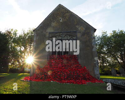 Murston, Kent, Großbritannien. 8. Oktober, 2018. UK Wetter: die Sonne hinter Murston alte Kirche, die mit Tausenden von Mohn von der Murston Herzen Poppy Projekt 2018 eingerichtet wurde, um die WW1 100 2018 zu gedenken. Murston Herzen Projekt und Vertiefungen in der Blüte arbeiten mit den Leuten von Swale und haben über 3000 einzigartige Mohnblumen, die jetzt einer von über 3000 gefallenen Helden aus der ganzen Swale Bereich, starben im Ersten Weltkrieg dar. Credit: James Bell/Alamy leben Nachrichten Stockfoto