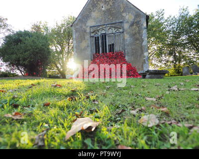 Murston, Kent, Großbritannien. 8. Oktober, 2018. UK Wetter: die Sonne hinter Murston alte Kirche, die mit Tausenden von Mohn von der Murston Herzen Poppy Projekt 2018 eingerichtet wurde, um die WW1 100 2018 zu gedenken. Murston Herzen Projekt und Vertiefungen in der Blüte arbeiten mit den Leuten von Swale und haben über 3000 einzigartige Mohnblumen, die jetzt einer von über 3000 gefallenen Helden aus der ganzen Swale Bereich, starben im Ersten Weltkrieg dar. Credit: James Bell/Alamy leben Nachrichten Stockfoto