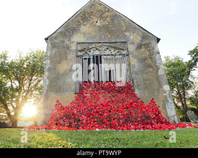 Murston, Kent, Großbritannien. 8. Oktober, 2018. UK Wetter: die Sonne hinter Murston alte Kirche, die mit Tausenden von Mohn von der Murston Herzen Poppy Projekt 2018 eingerichtet wurde, um die WW1 100 2018 zu gedenken. Murston Herzen Projekt und Vertiefungen in der Blüte arbeiten mit den Leuten von Swale und haben über 3000 einzigartige Mohnblumen, die jetzt einer von über 3000 gefallenen Helden aus der ganzen Swale Bereich, starben im Ersten Weltkrieg dar. Credit: James Bell/Alamy leben Nachrichten Stockfoto