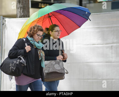 Zwei Mädchen zu Fuß zusammen unter einem Regenbogen Regenschirm. Wien, Österreich Stockfoto