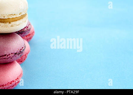 Französische Macarons auf blauem Hintergrund. Trendy Dessert. Süße Kuchen. Stockfoto