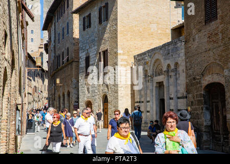 Tour Gruppe alle tragen gelbe Schals zu Fuß durch die historische Altstadt auf dem Hügel von San Gimignano in der Toskana, süd-westlich von Florenz, Italien, Europa Stockfoto