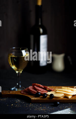 Wurst, Käse, Salami, Oliven und ein Glas Wein auf einem dunklen Tabelle schließen Stockfoto