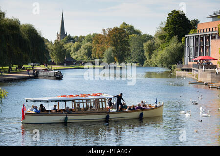 Ein Fluss Kreuzfahrt Schiff unter Touristen und Besucher entlang des Flusses Avon in Stratford-upon-Avon auf einem hellen herbstlichen Tag. Stockfoto