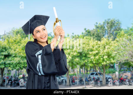 Schöne asiatische Schüler Mädchen feiern Ihren Abschluss mit Kappe und Diplom Blättern auf dem Campus Stockfoto