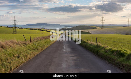 Ein Feldweg und eine Linie von strommasten Kreuz landwirtschaftliche Felder und Weiden auf der hügeligen Landschaft der Dorset Downs Hügeln über Weymou Stockfoto