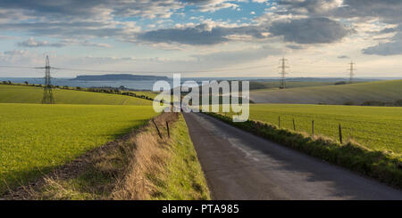 Ein Feldweg und eine Linie von strommasten Kreuz landwirtschaftliche Felder und Weiden auf der hügeligen Landschaft der Dorset Downs Hügeln über Weymou Stockfoto