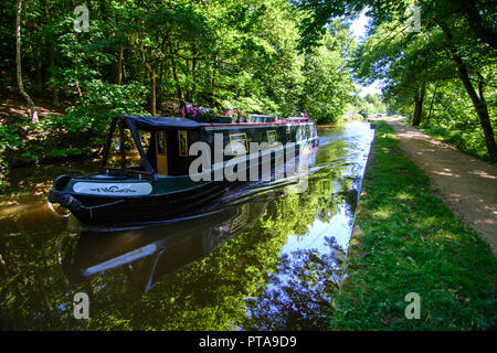 Shipley, England - 30. Juni 2015: Einem traditionellen Narrowboat durchläuft im Schatten der Wälder entlang der Leeds und Liverpool Canal bei Shipley in der Nähe von Br Stockfoto