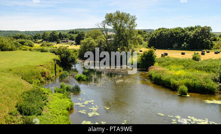 Der Fluss Stour führt durch Felder von Weide und Heuballen auf die landwirtschaftliche Landschaft von Dorset von Blackmore Vale, mit Shillingstone Station und Stockfoto