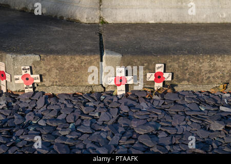 ​Remembrance Tag Roter Mohn auf kleine hölzerne Kreuze neben einem Kriegerdenkmal in Chichester, West Sussex, UK. Stockfoto