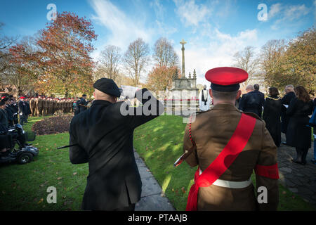 Saluting-Veteran. Ein Veteran begrüßt vor einem Kriegsdenkmal während eines Gedenksonntagsgottesdienstes in Chichester, West Sussex, Großbritannien. Stockfoto