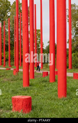 Southfield, Michigan - eine Frau geht durch rote Pole Park, ein öffentliches Kunstprojekt mit alten utility Pole und Baumstümpfen angelegt. Stockfoto