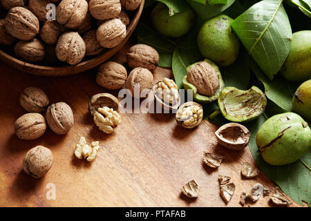 Frische Walnüsse mit und ohne Schalen auf einem Holz- Oberfläche. Walnüsse, geschält und ohne Schale. Stockfoto