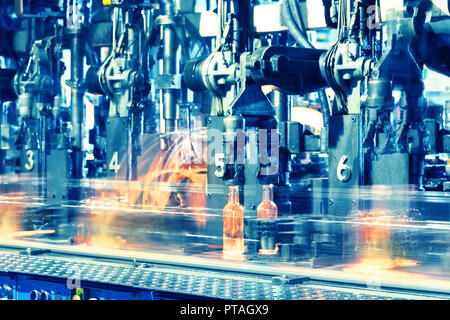 Heißes Glas Flaschen auf Glas. Hot red Flaschen bewegen sich entlang der Förderanlage in der Fabrik. Toning Stockfoto