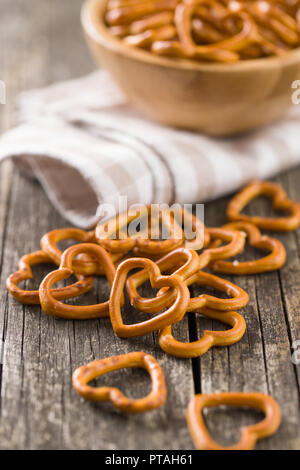 Herzförmige Brezel auf alten Holztisch. Stockfoto