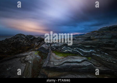 Sonnenuntergang von den Trondheimsfjorden, Strand in Vaeresholmen, Vaere. Lange Belichtung auf fließende Wolken und welligen Wasser. Stockfoto