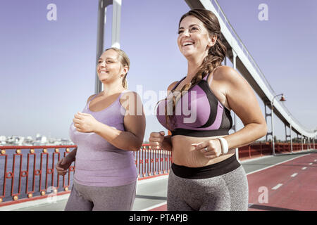 Positive freudige Frauen zusammen, die auf der Brücke Stockfoto
