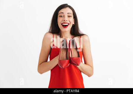 Image der Jungen aufgeregt schockiert Schöne hübsche Frau posiert isoliert halten roten Schuhe in den Händen. Stockfoto
